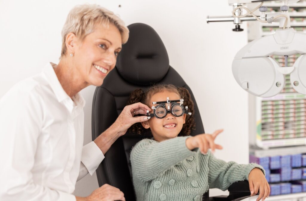 Child sitting in an optometrists chair wearing vision testing glasses during an eye exam with the optometrist