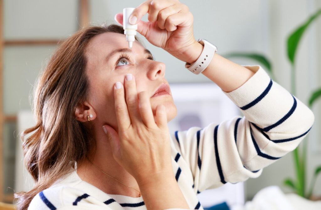 A person holds up a container of eye drops above their dry eye