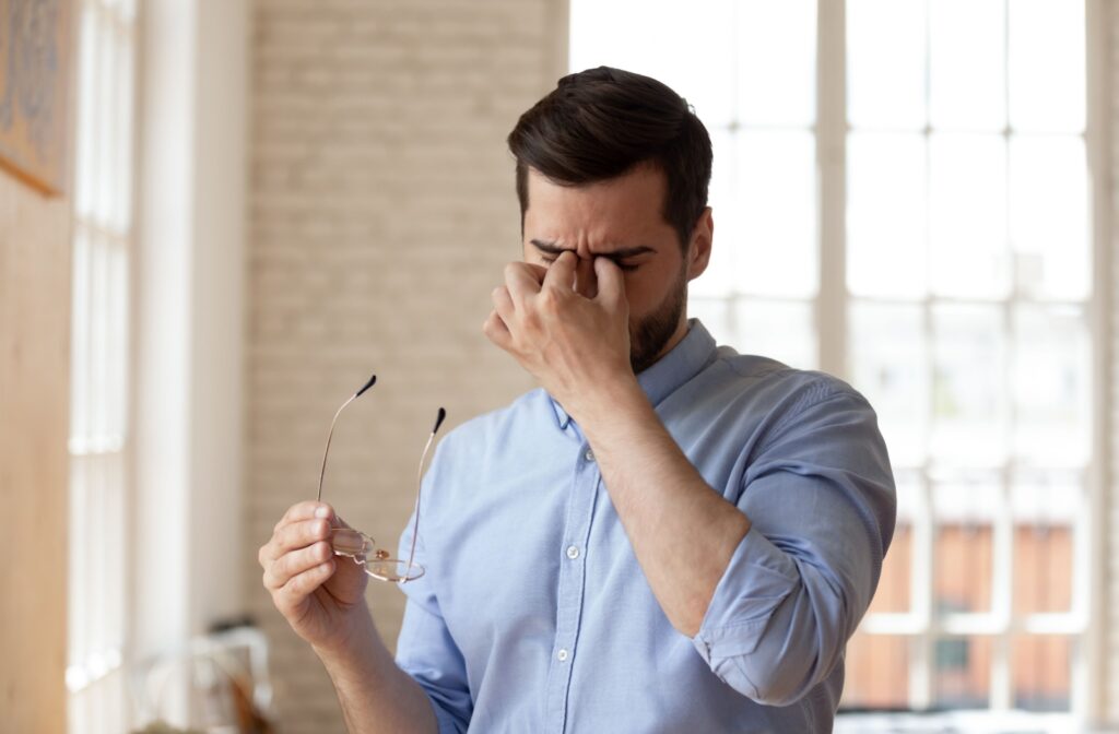 A person removes their glasses and rubs their dry eyes