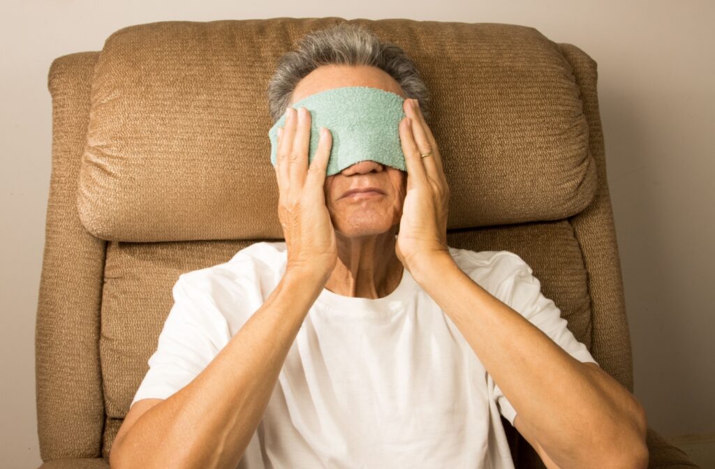 A person sitting in a recliner chair with a warm towel over their eyes
