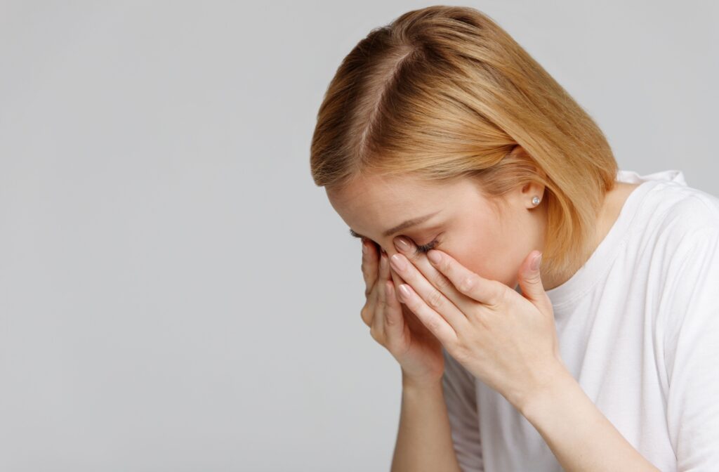 A person leaning over as they rub their irritated eyes