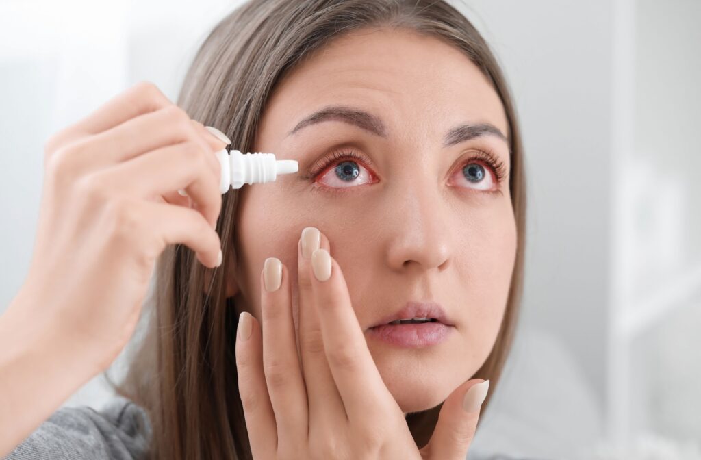 A person with red irritated eyes putting eye drops to sooth their dry eyes