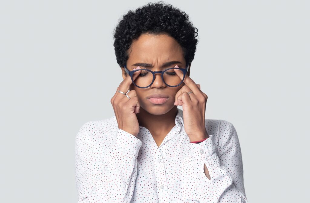 A person rubbing their dry eyes behind their glasses